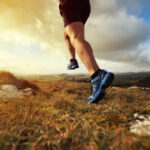 Bežec v teniskách na prírodnom chodníku pri západe slnka, symbolizujúci pohodlie a ľahkosť.