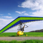 Osoba letí na rogale ponad hory počas slnečného dňa.