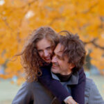 Šťastná žena rozbaľuje vkusne zabalený darček s veľkou mašľou od svojho partnera v útulnej obývačke.